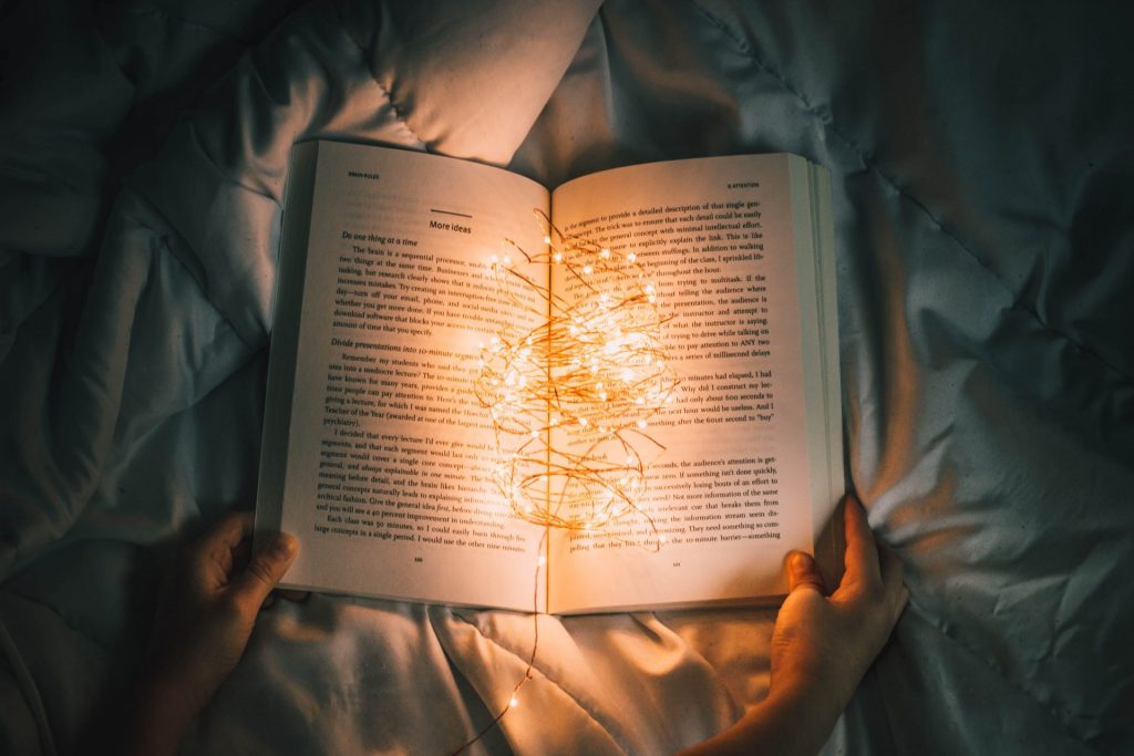 Ein Buch liegt mit einer Lichterkette in der Mitte aufgeschlagen auf dem Bett